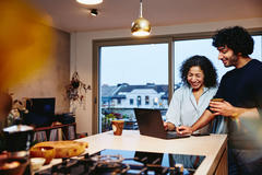 A man and a woman laughing, looking at a laptop