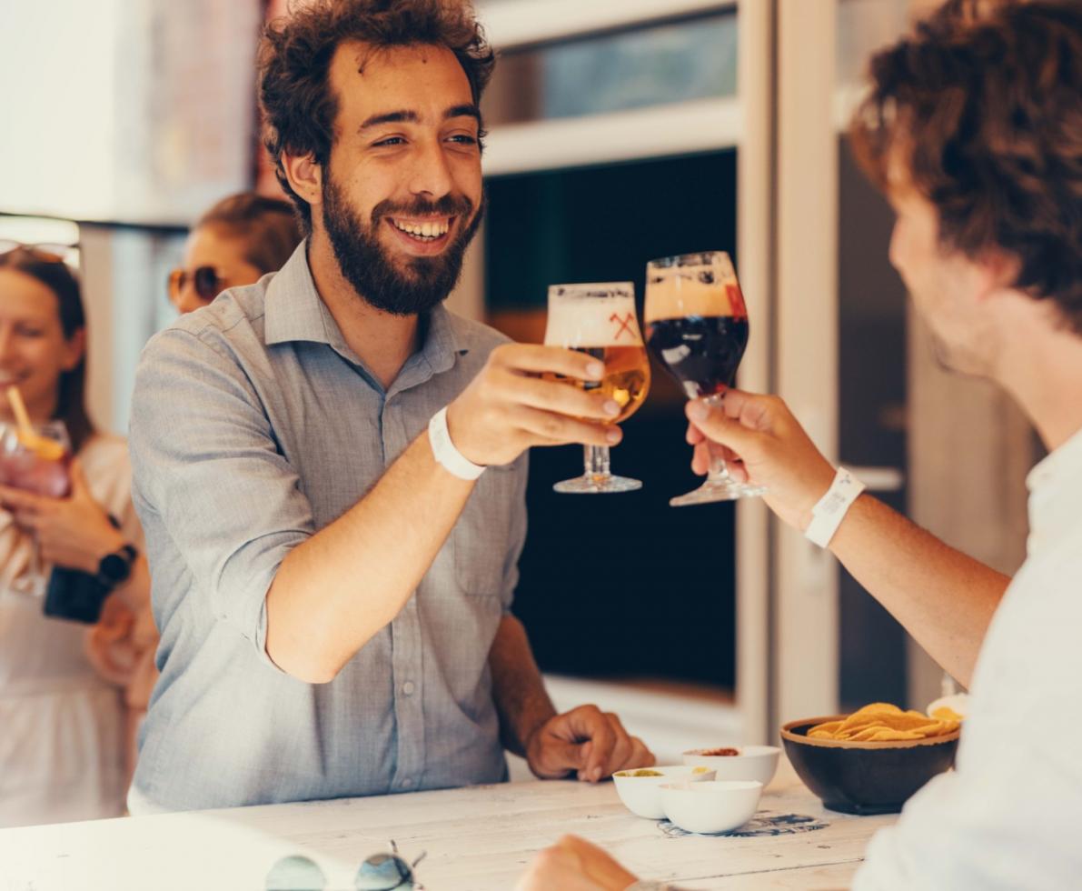 2 men at an event proposing a toast with beer glasses
